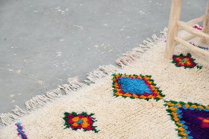 Cream-colored DecorBites™ moroccan handmade traditional Azilal rug with vibrant geometric patterns and long white fringe