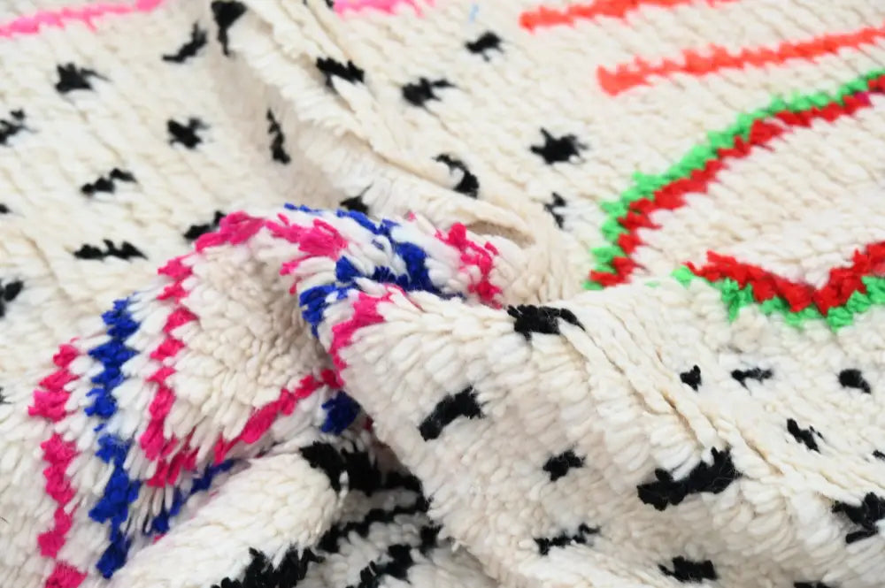 A moroccan handmade traditional azilal rug with a cream base and bold geometric patterns in multiple colors by decorbites