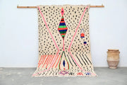 A vibrant moroccan handmade traditional azilal rug by decorbites with cream base and bold pink black green blue red patterns