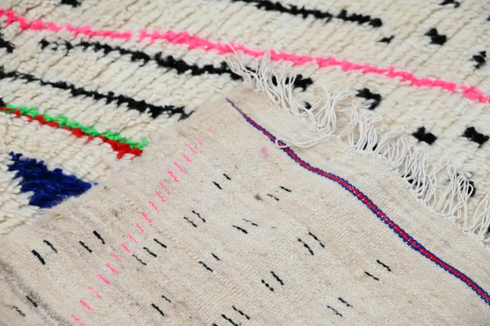 Beige moroccan handmade traditional azilal rug with bold geometric patterns in black pink green red and blue threads