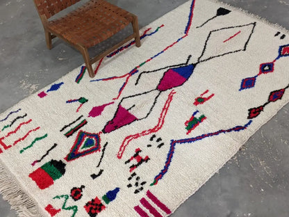 A vibrant cream-colored moroccan handmade azilal rug with bold geometric patterns in pure natural wool
