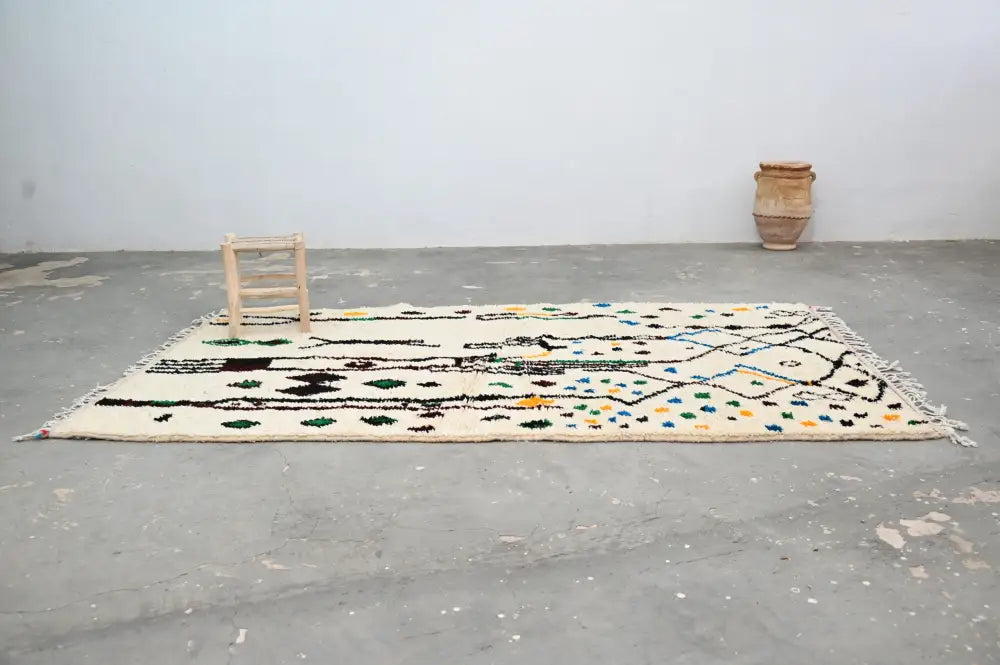 Cream-colored DecorBites™ moroccan handmade traditional azilal rug with black green and blue geometric patterns and fringed edges
