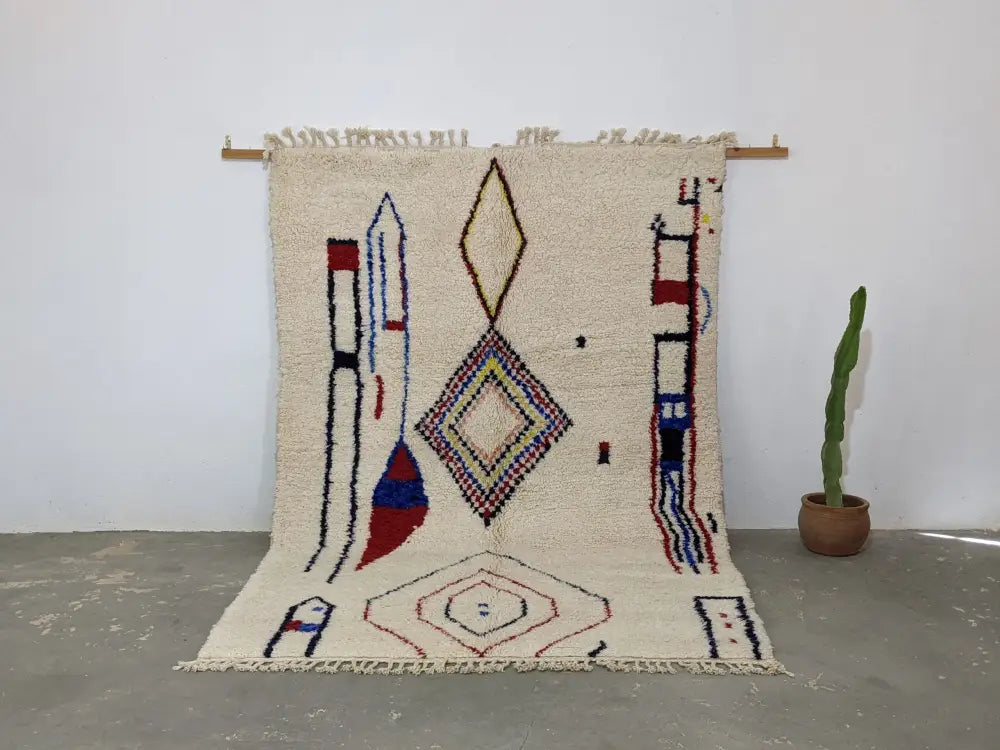 Cream-colored moroccan handmade traditional azilal rug with red blue and brown geometric patterns on woolen surface