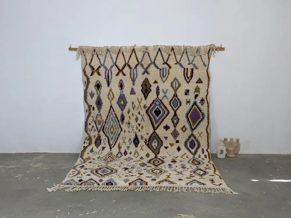 Beige moroccan handmade traditional azilal rug with intricate purple blue and brown geometric patterns and fringed edges