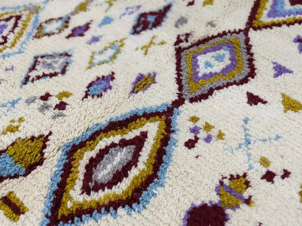 Cream-colored moroccan handmade traditional azilal rug with maroon gold blue and purple geometric patterns 300 x 205 cm