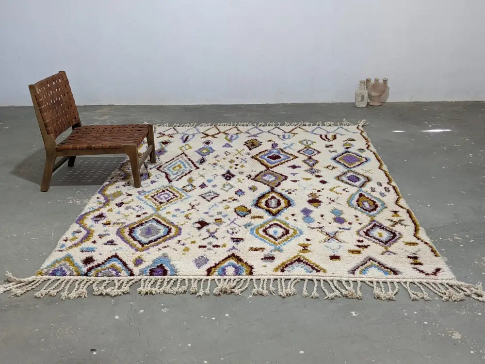 Cream-colored moroccan handmade traditional azilal rug with intricate purple blue brown geometric patterns and long fringe edges