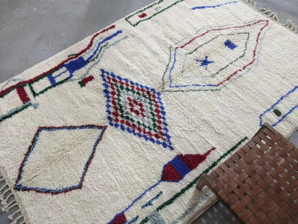 Cream-colored wool moroccan handmade traditional azilal rug with intricate red blue and green geometric patterns 300 x 210 cm