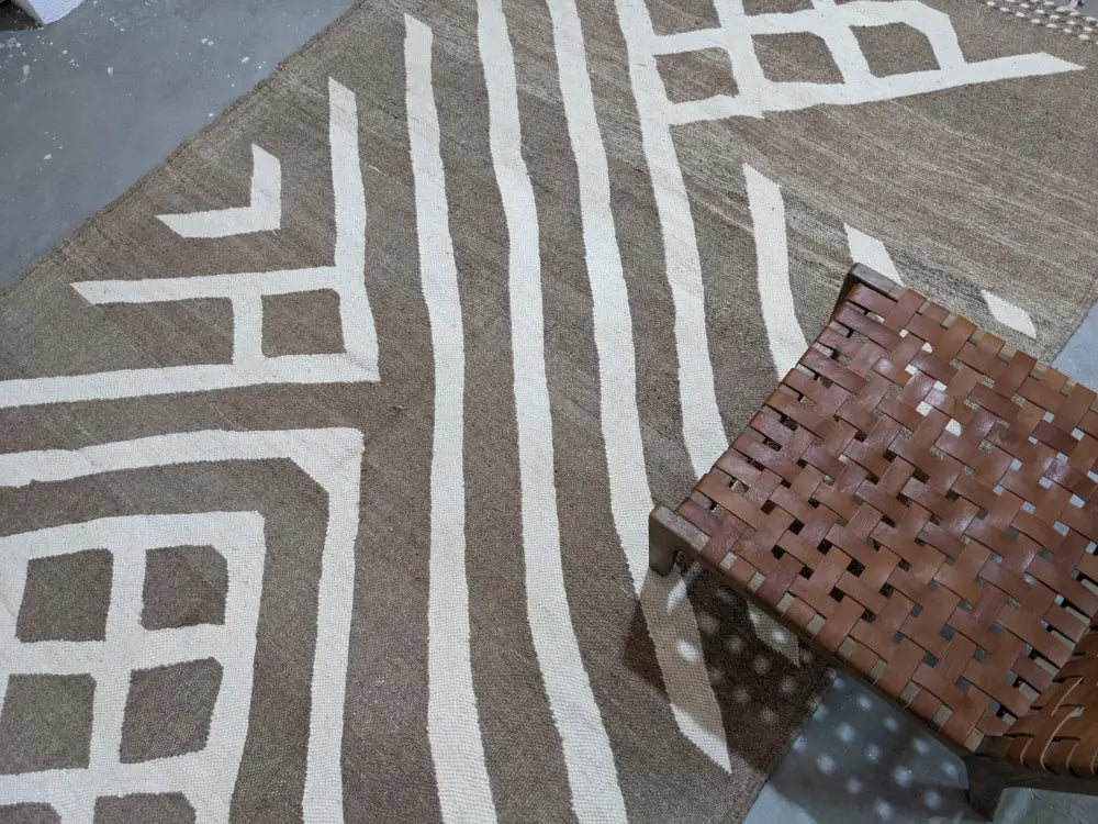 Brown woven leather stool on a moroccan handmade traditional azilal rug with geometric patterns in brown and beige