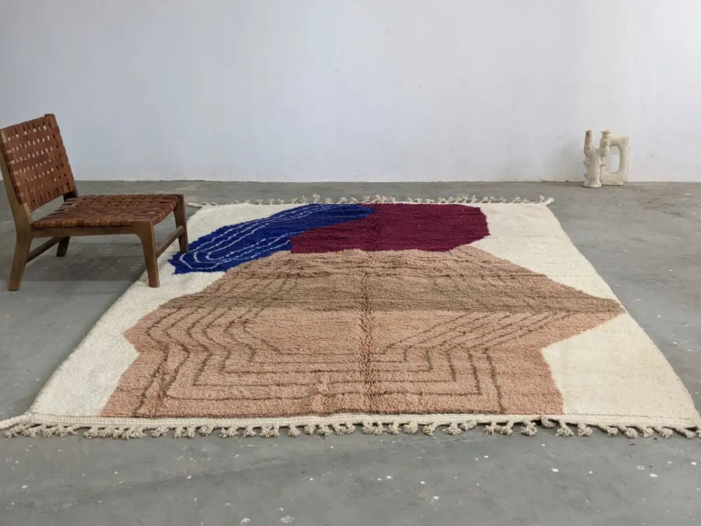 A cream-colored moroccan handmade traditional azilal rug with bold blue maroon and beige geometric patterns by DecorBites