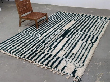 A chunky moroccan handmade traditional azilal rug with bold black and cream wool stripes and tassels by DecorBites