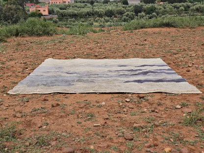 Decorbites™ moroccan handmade beni mrirt rug with textured beige base and faded blue-gray stripes on dry earth