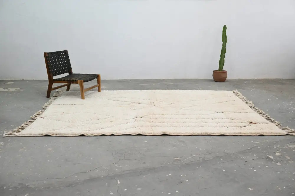 Cream-colored moroccan handmade beni ouarain rug with subtle geometric patterns and fringed edges 283 x 211 cm