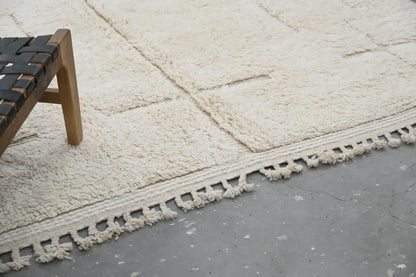 Cream-colored plush wool beni ouarain carpet with textured surface and decorative tassels moroccan handmade rug