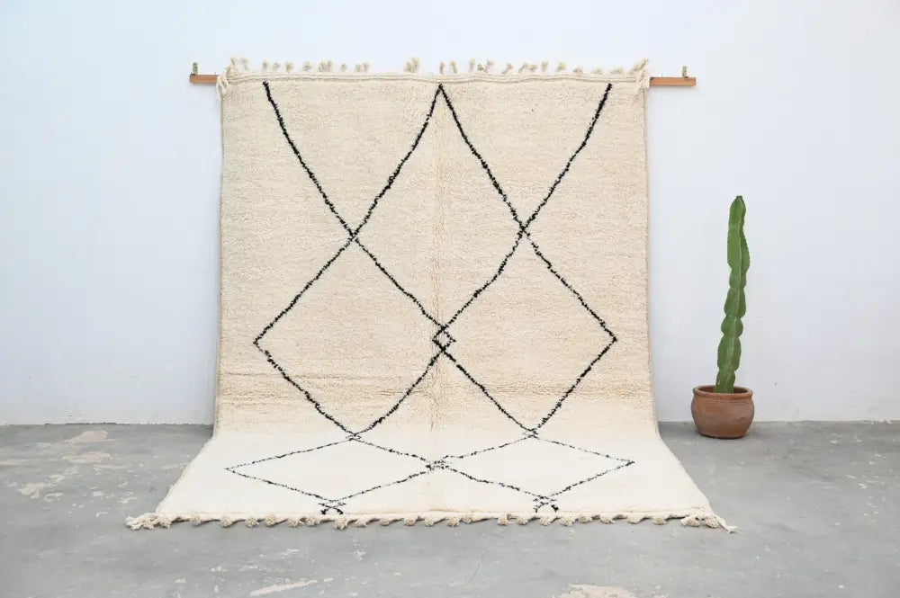 Cream-colored beni ouarain carpet with black geometric diamond patterns and fringed edges moroccan handmade rug