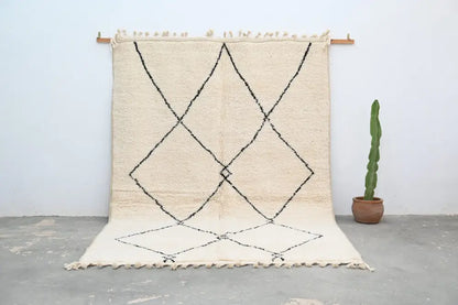 Cream-colored beni ouarain carpet with black geometric diamond patterns and fringed edges moroccan handmade rug