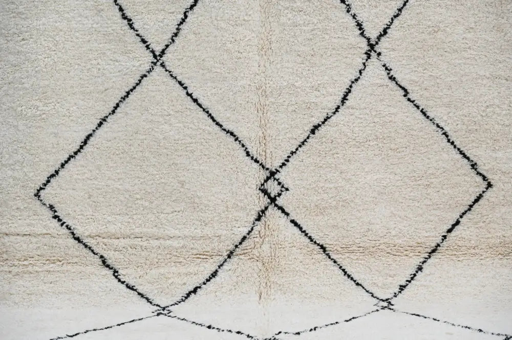 Cream-colored moroccan handmade beni ouarain carpet with textured fluffy surface and bold black geometric diamond patterns