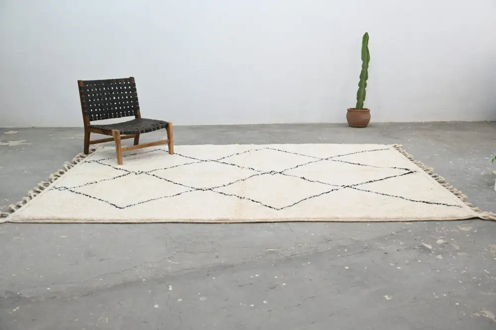 Cream-colored moroccan handmade beni ouarain carpet with black geometric diamond patterns and fringed edges 310 x 215 cm