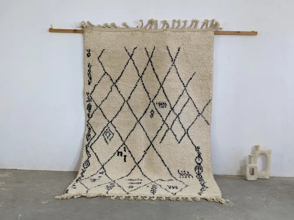 Beige moroccan handmade beni ouarain rug with black geometric patterns and fringed edges 244 x 157 cm