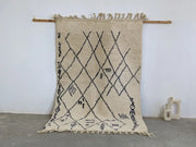 Beige moroccan handmade beni ouarain rug with black geometric patterns and fringed edges 244 x 157 cm