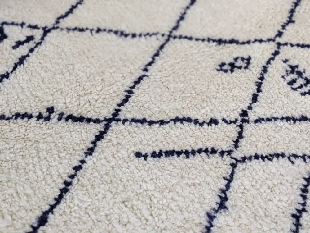 Cream-colored moroccan handmade beni ouarain rug with plush texture and dark blue geometric diamond stitched pattern