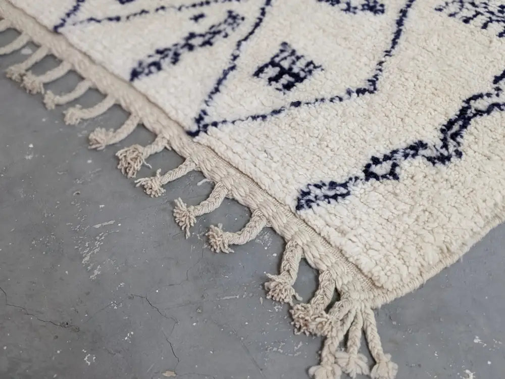 Cream-colored moroccan handmade beni ouarain rug with navy blue geometric patterns and fringed edges 244 x 157 cm