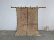 Beige plush wool beni ouarain rug with fringed edges hanging on wooden rod from decorbites traditional collection