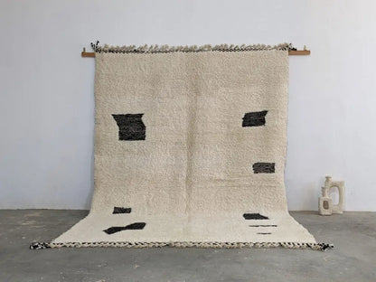 Cream-colored moroccan handmade beni ouarain rug with bold black geometric patches and fringed edges 290 x 210 cm