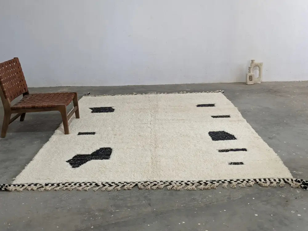 Cream-colored beni ouarain rug with black geometric patterns and fringed edges moroccan handmade traditional design
