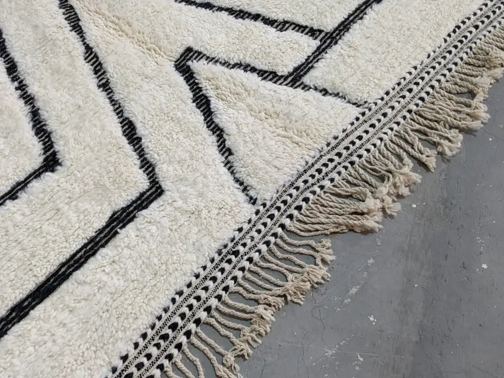 Cream-colored beni ouarain rug with bold black geometric patterns and fringe border moroccan handmade traditional design