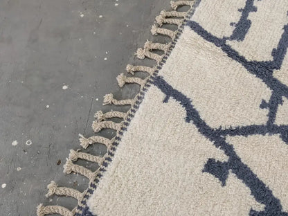 Cream-colored beni ouarain rug with navy blue geometric patterns and fringed edge moroccan handmade traditional design