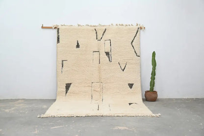 Cream-colored moroccan handmade beni ouarain rug with black geometric patterns and fringed edges 300 x 200 cm
