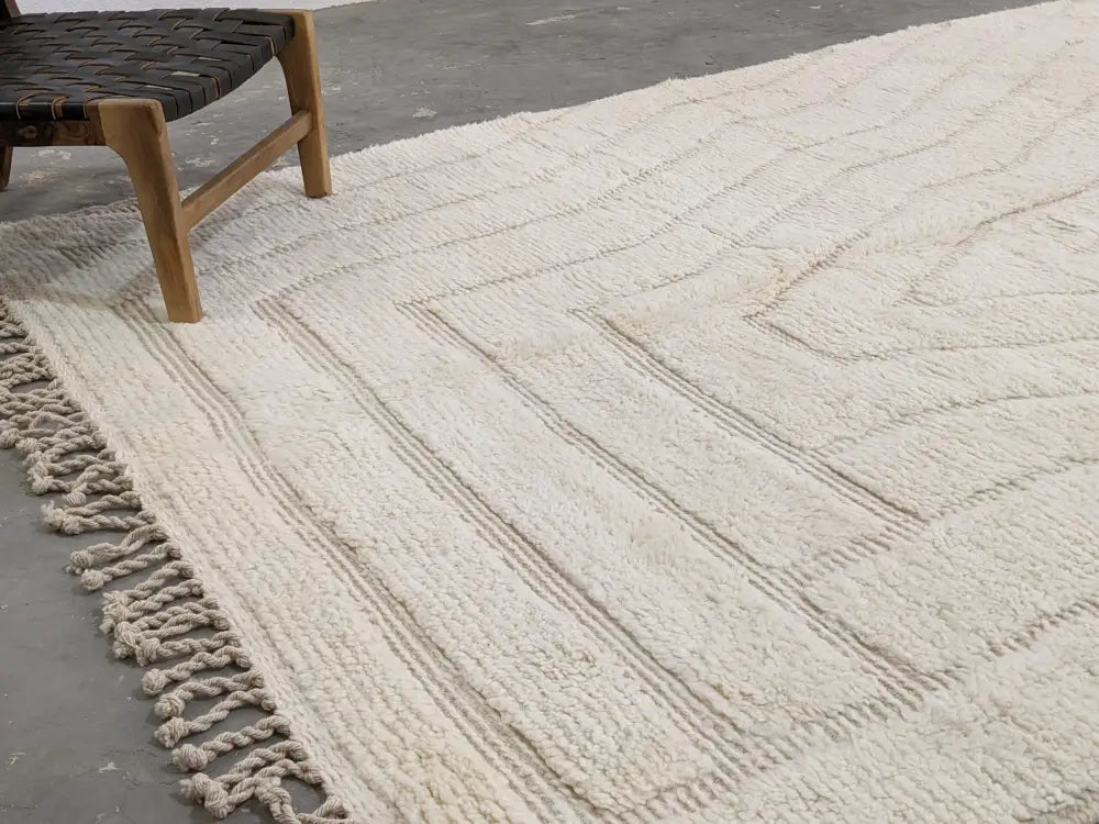 Cream-colored moroccan handmade beni ouarain rug with handwoven wool, textured geometric pattern, and fringed edges