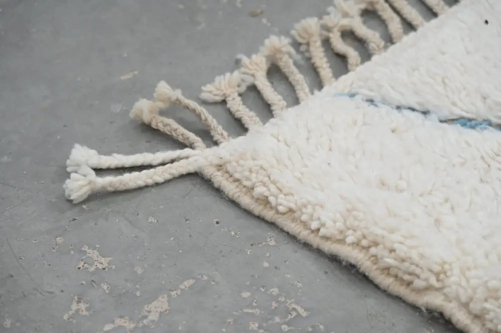 Cream-colored fluffy moroccan handmade beni ouarain rug with fringed edges and subtle blue stitching 300 x 205 cm