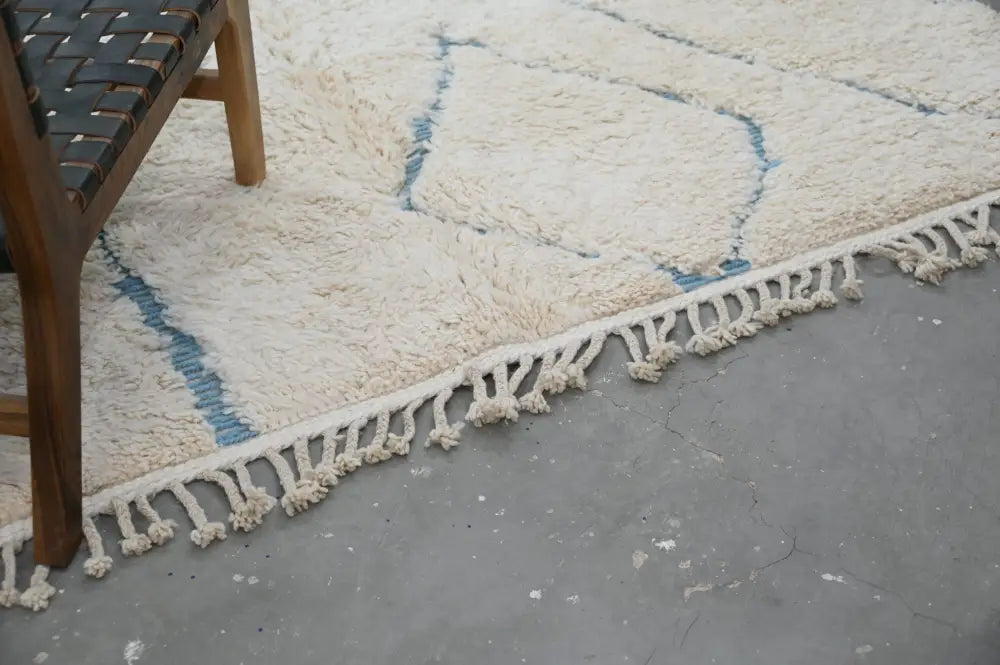 Cream-colored shaggy beni ouarain rug with blue geometric patterns and fringed edges moroccan handmade traditional style