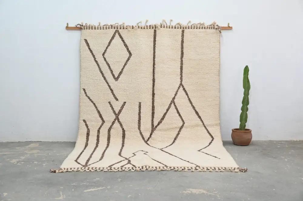 Beige moroccan handmade beni ouarain rug with bold brown geometric patterns and fringed edges by DecorBites™