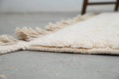 Cream-colored moroccan handmade beni ouarain rug with plush wool texture and fringed edges 300 x 217 cm