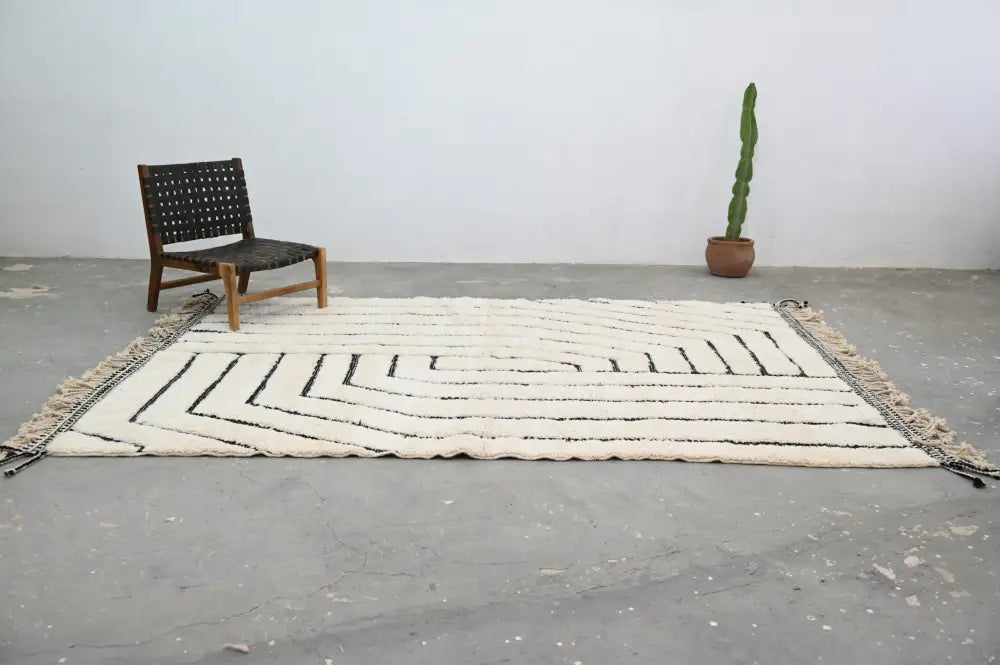 Cream-colored beni ouarain rug with black geometric zigzag patterns and fringed edges moroccan handmade wool rug