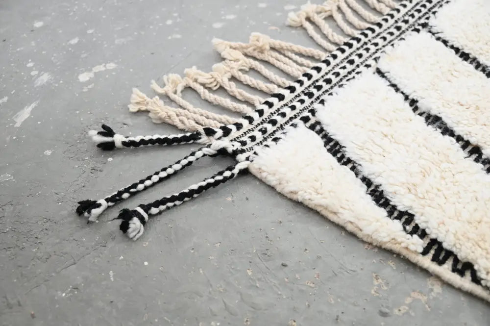 A cream and black striped beni ouarain rug with textured fringed edges moroccan handmade by DecorBites™