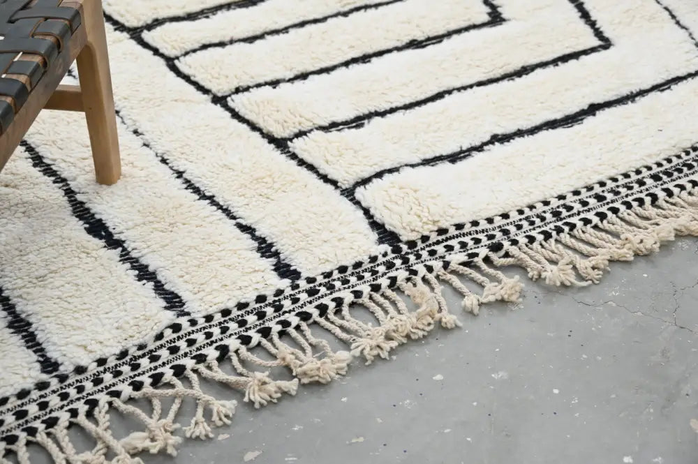 Cream-colored plush wool beni ouarain rug with bold black geometric patterns and fringe border moroccan handmade design
