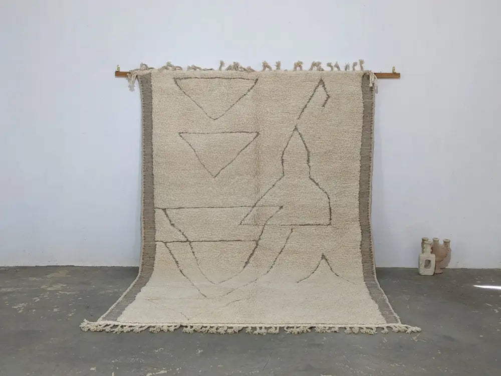 Beige moroccan handmade beni ouarain rug with geometric black line patterns and fringed edges 305 x 204 cm