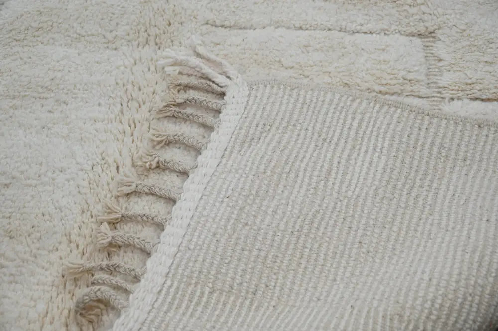 Cream-colored thickly woven beni ouarain rug with textured surface and fringed edge by decorbites 307 x 205 cm