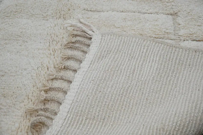 Cream-colored thickly woven beni ouarain rug with textured surface and fringed edge by decorbites 307 x 205 cm