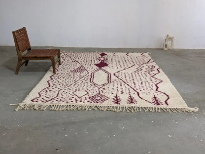 Cream-colored beni ouarain rug with maroon geometric and tree motifs and fringed edges from decorbites