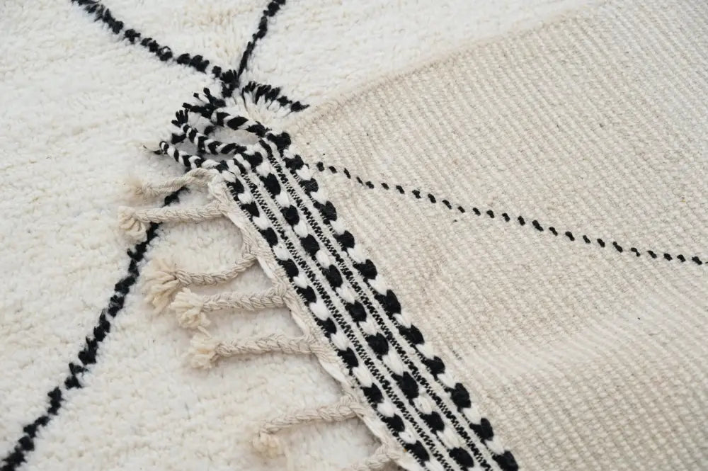Cream-colored moroccan handmade beni ouarain rug with black geometric patterns and fringed edges 309 x 204 cm