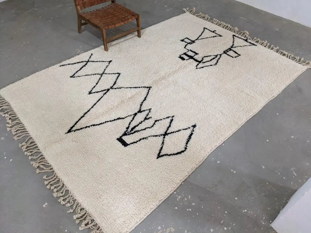 Cream-colored moroccan handmade beni ouarain rug with black geometric patterns and fringed edges 310 x 210 cm