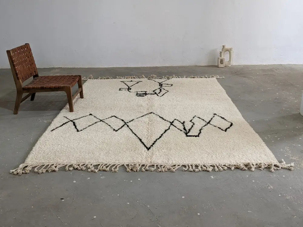 Cream-colored moroccan handmade beni ouarain rug with black geometric patterns and fringed edges 310 x 210 cm