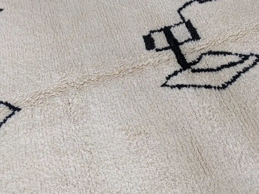 Cream-colored moroccan handmade beni ouarain rug with bold black geometric patterns measuring 310 x 210 cm