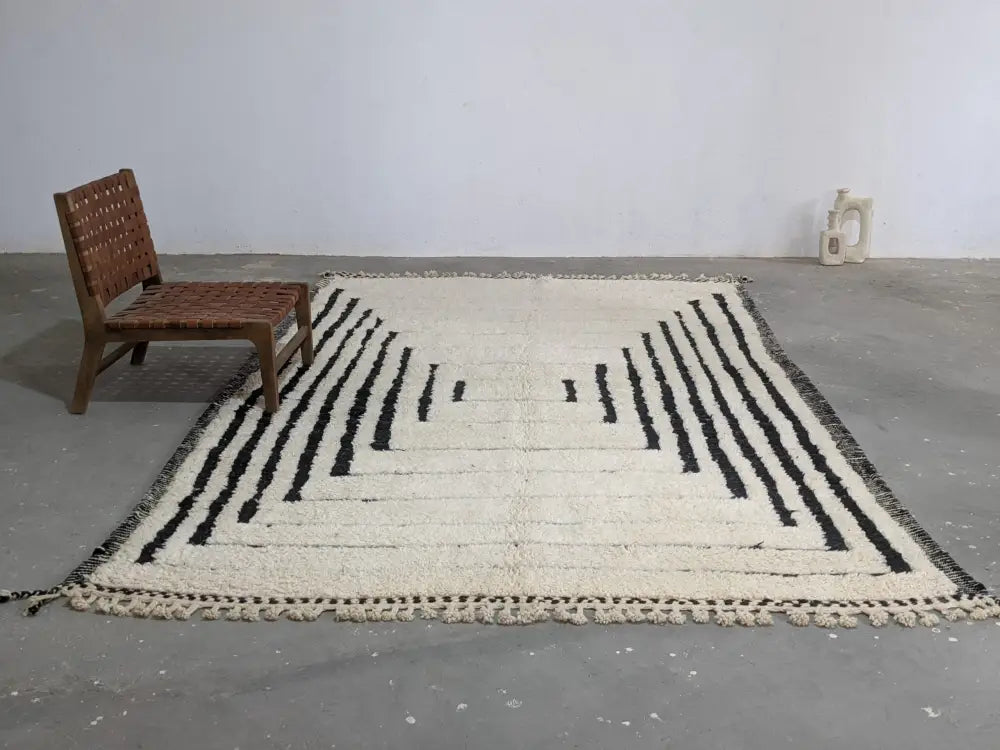 Cream-colored beni ouarain rug with bold black geometric stripes and fringed edges moroccan handmade traditional design