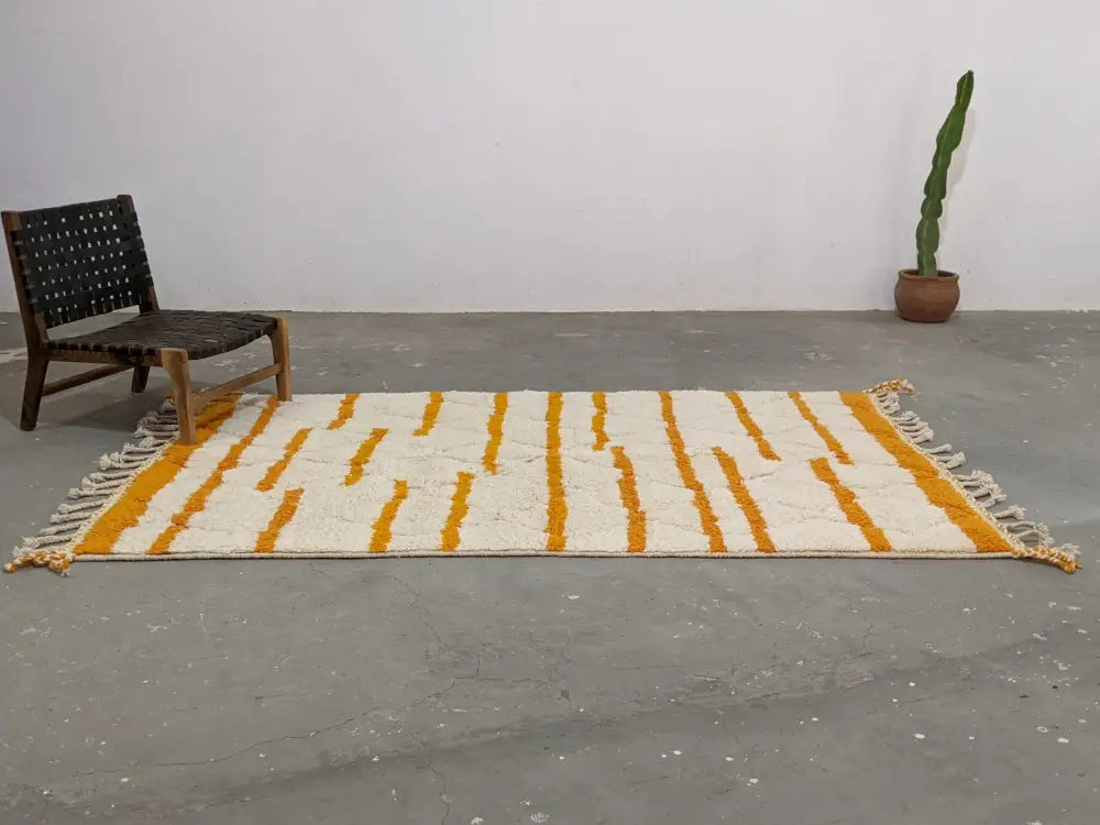 Cream-colored moroccan handmade beni ouarain rug with bold orange vertical stripes and fringed edges 248 x 158 cm