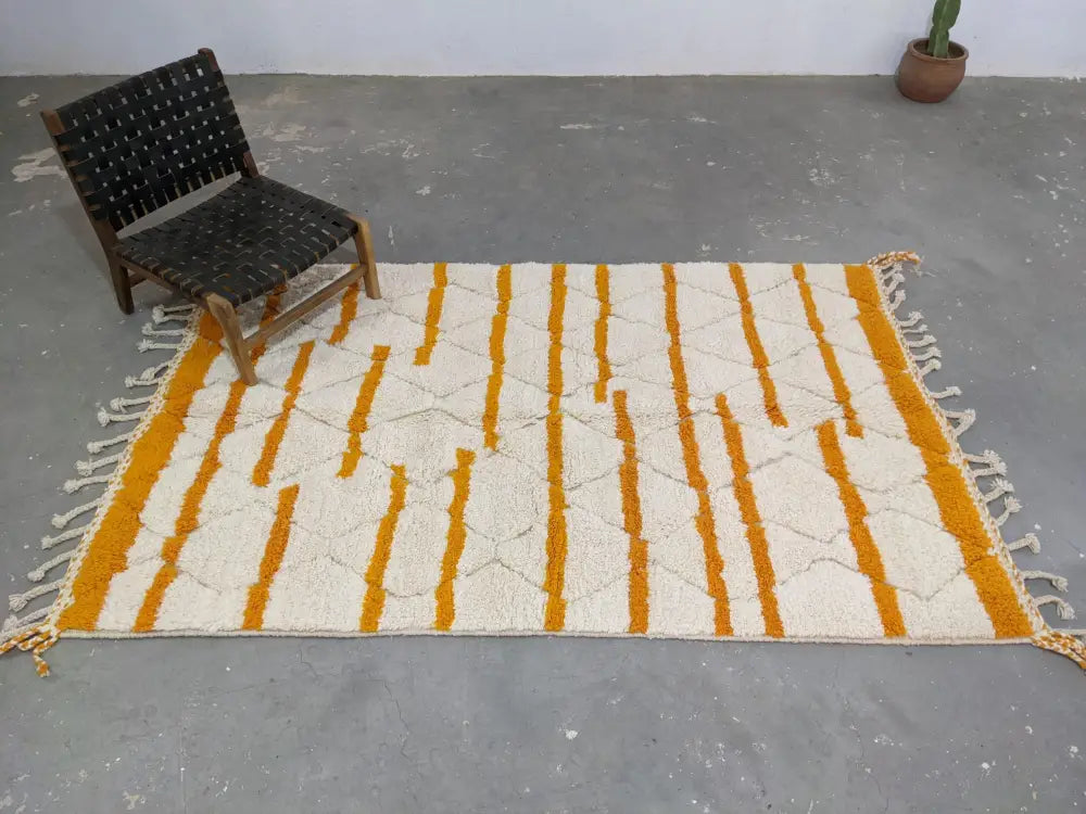 A moroccan handmade beni ouarain rug with cream and mustard yellow stripes and fringed edges by decorbites